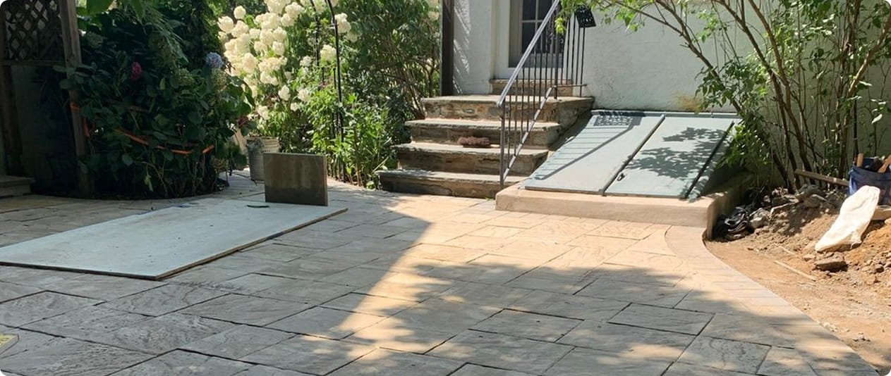 Stone patio with a concrete ramp leading to a house entrance