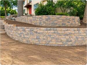 Stacked stone retaining walls built on a slope in front of a residential home.