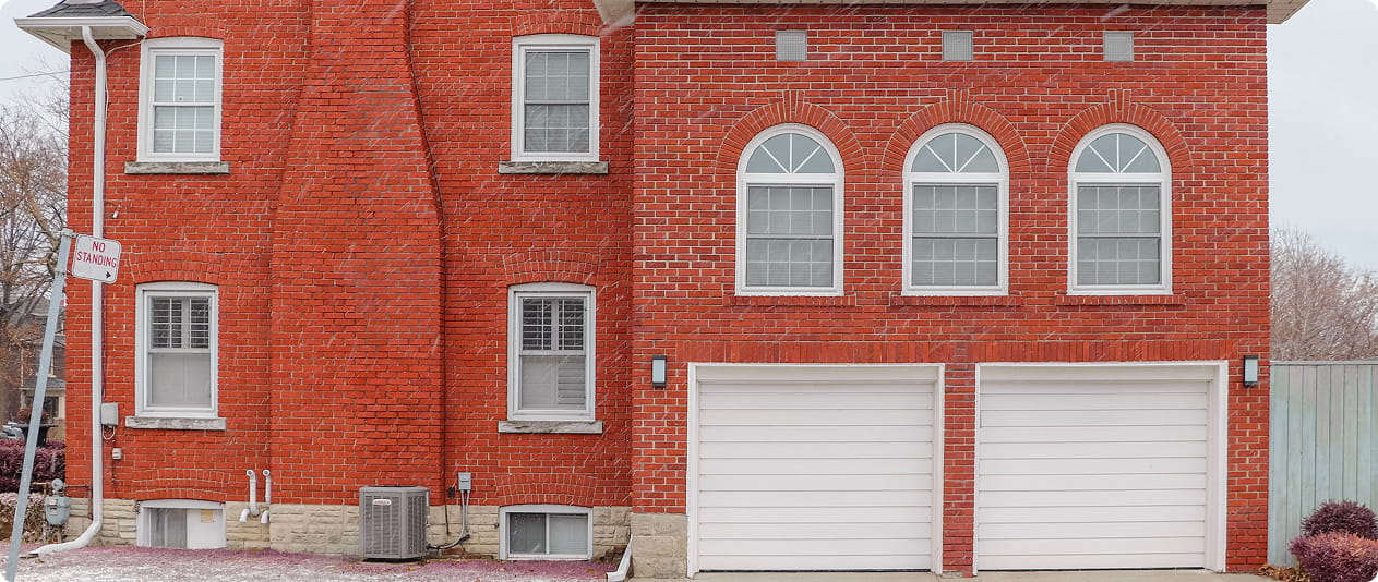 Red brick building with two white garage doors and arched windows